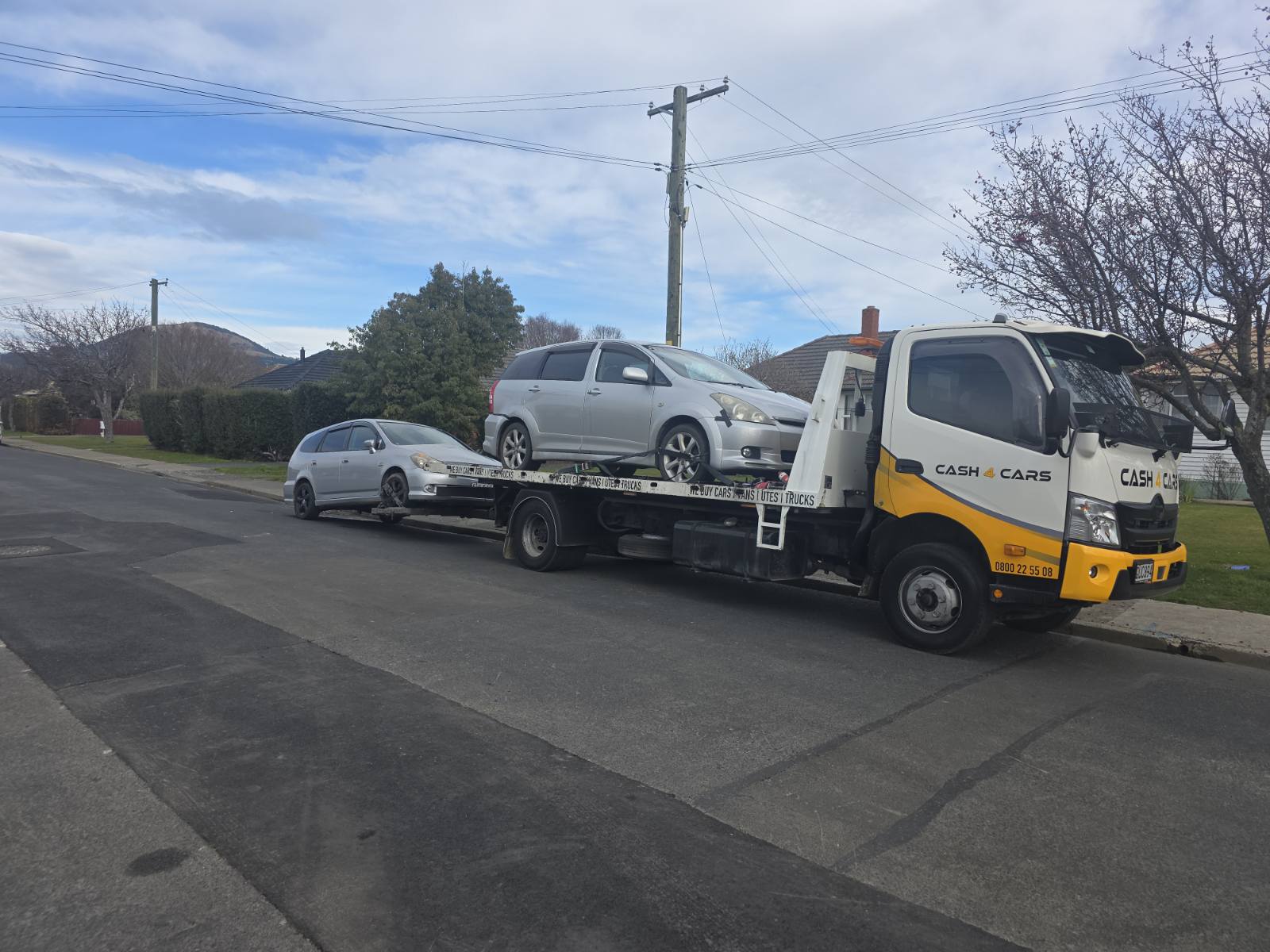 Cash4Cars tow truck loaded with two silver cars on an Invercargill street