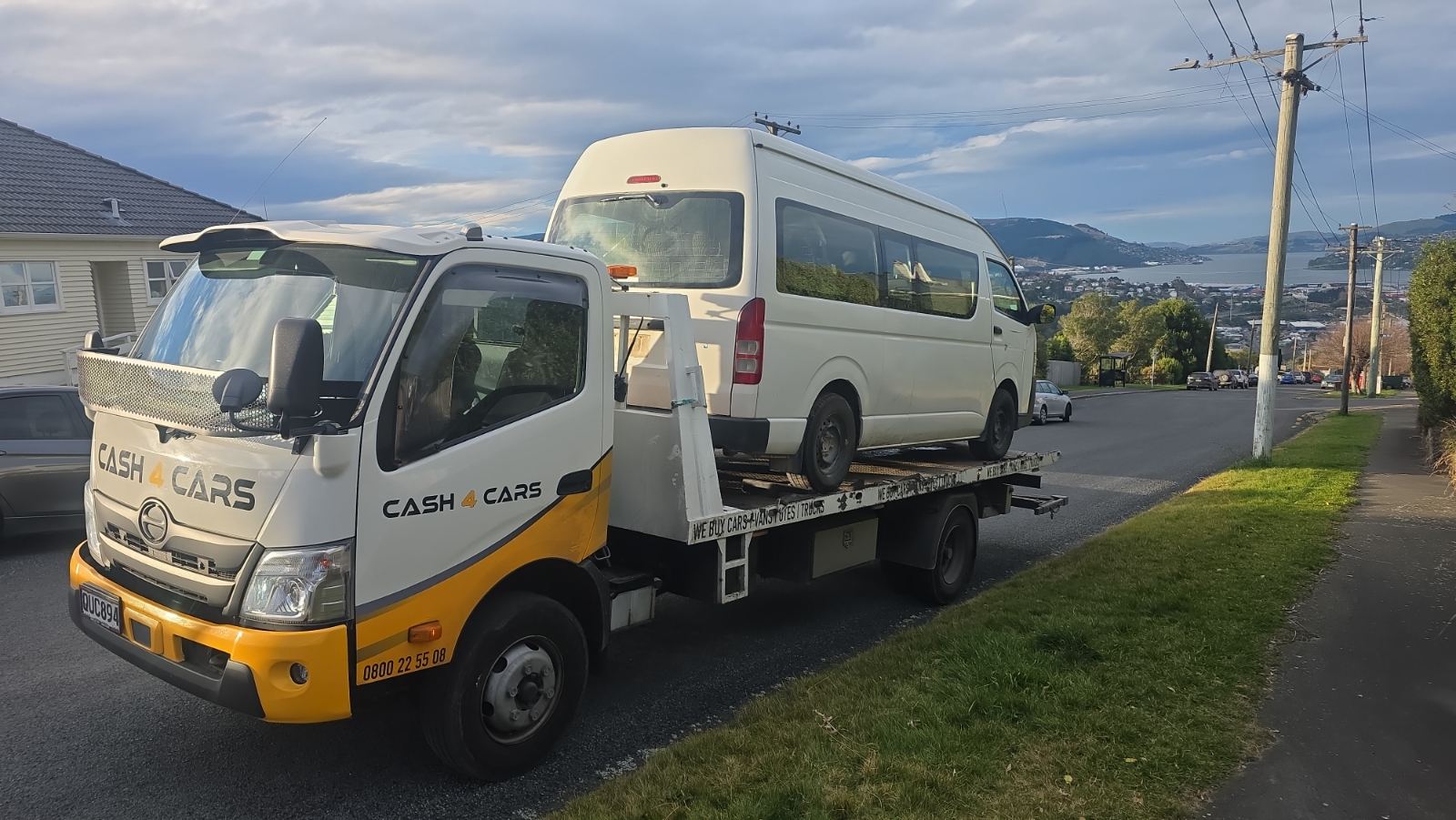 Cash4Cars tow truck collecting a van with harbour views behind